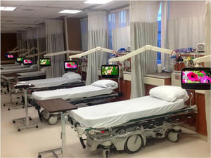 A semi-private patient room design showcasing tvs and tv mounting arms