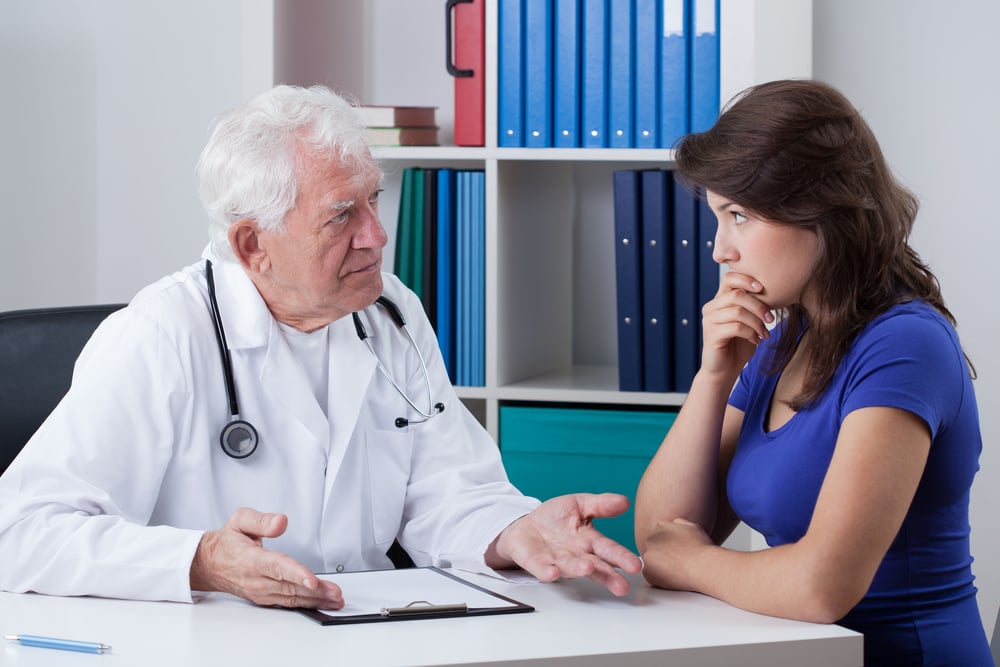 Senior male doctor talking with worried patient