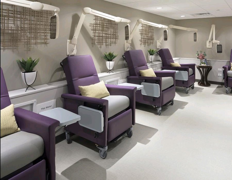 A dialysis center with a row of purple dialysis chairs, each with an arm-mounted PDi medTV16 installed.