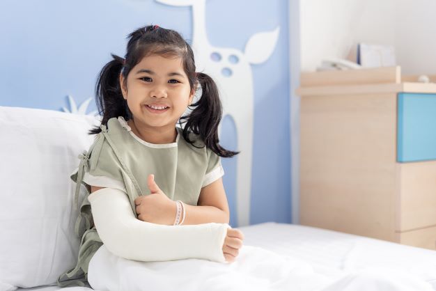 Young girl patient in bed with arm cast