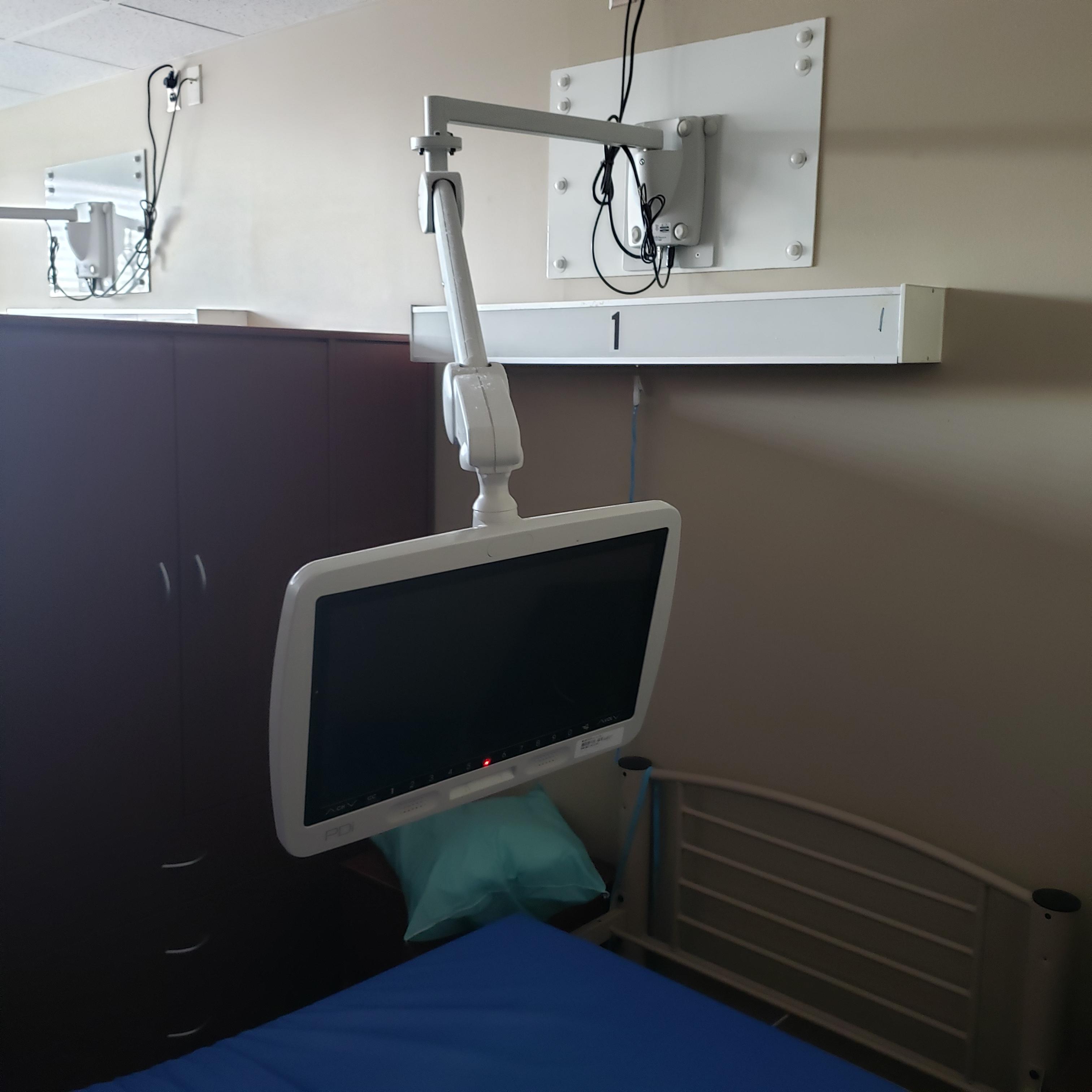A medTV19 by PDi next to a patient bed at a Veterans Hospital, mounted to the wall with a PDi horizontal wall arm mount.